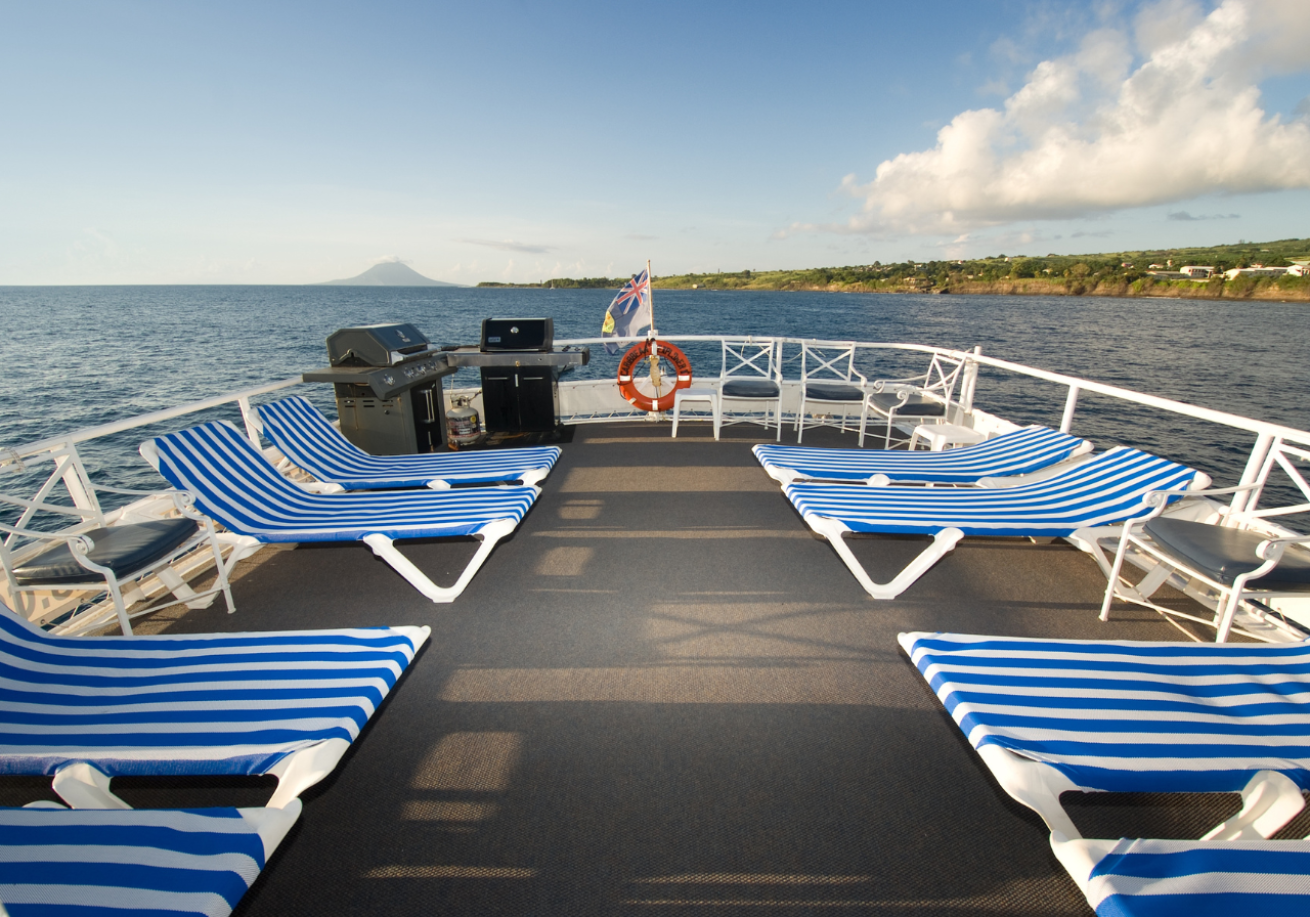 A deck of a boat with chairs on the water