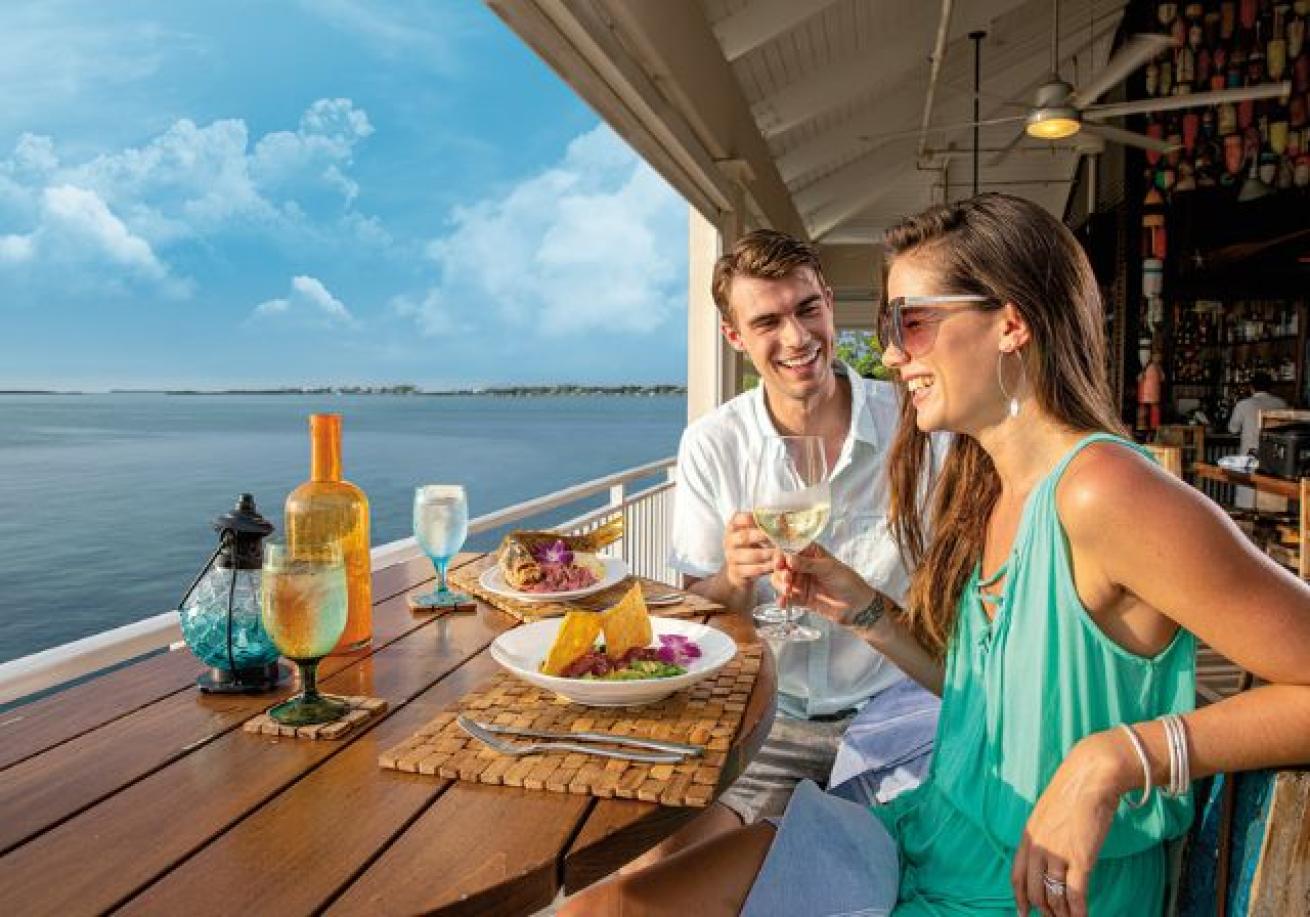 A person and person sitting at a table with food and drinks