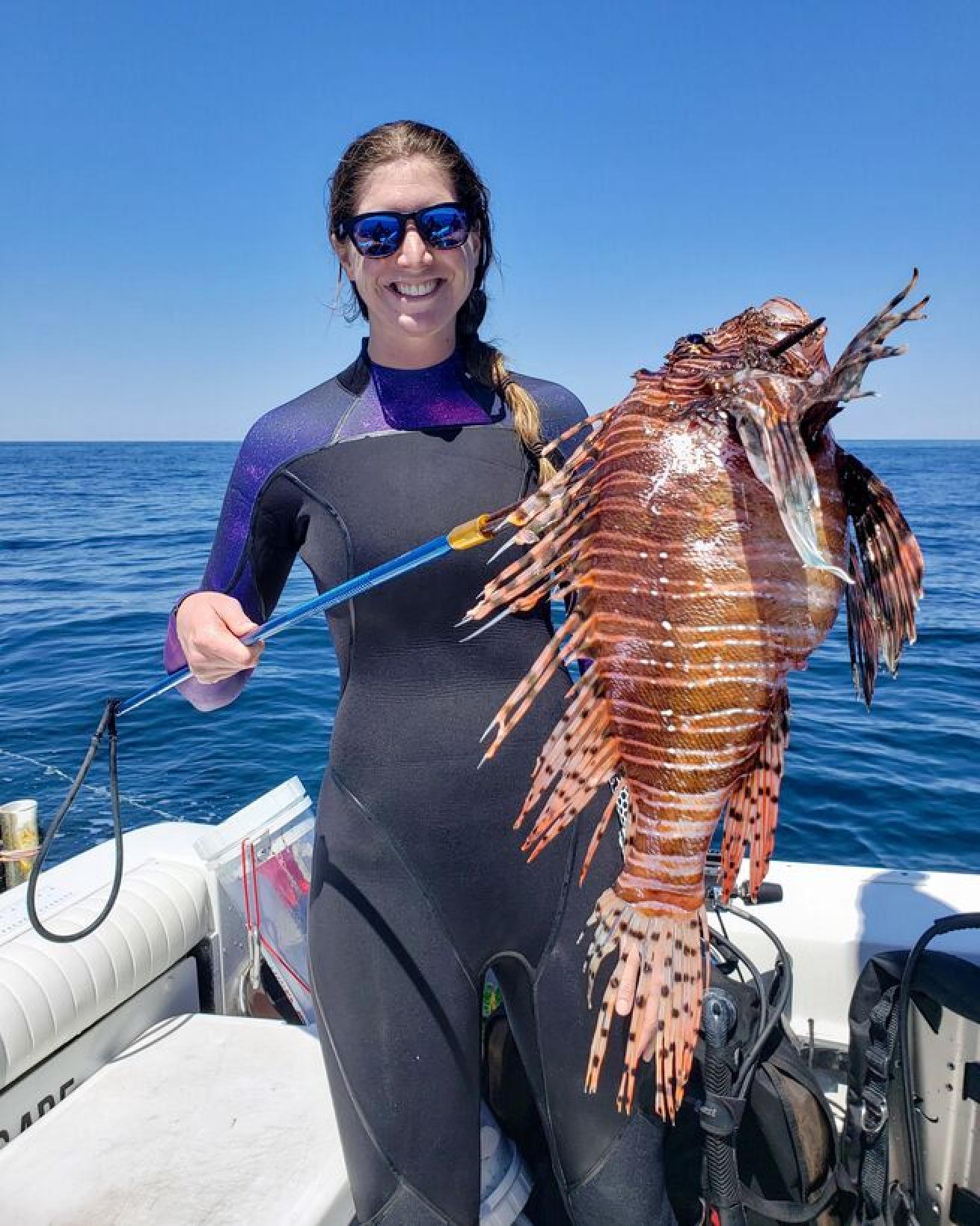 First-time lionfish hunter, Becca Hurley proudly displays a large lionfish post-dive.